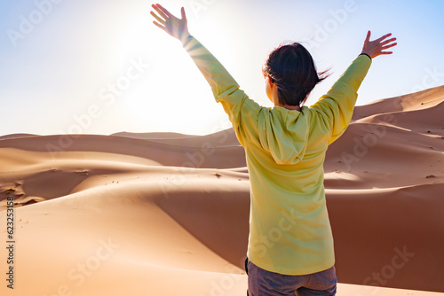 砂漠で朝日を浴びる女性