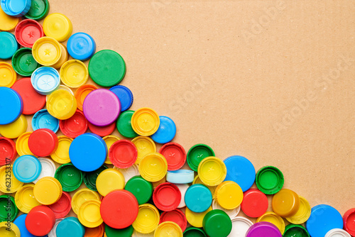 Colorful bottle caps background cardboard box. Used PET recycling plastic bottle cap plastic lids. Garbage PET waste recycling bottle cap sorting waste plastic garbage collection. Recyclable materials