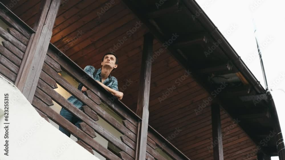 Handsome man on balcony of a country house admiring beautiful landscape on background Handsome man on balcony of a country house admiring beautiful landscape on background