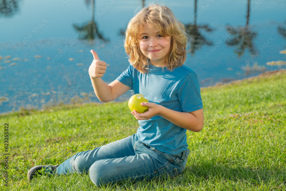 Picking apple. Excited kid picking apple. Child bitten apple outdoor on summer green grass background. Blonde little boy eat apple. Picking apple. Excited kid picking apple. Child bitten apple outdoor on summer green grass background. Blonde little boy eat apple.