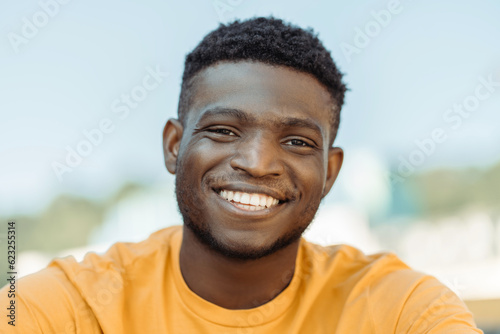Handsome smiling African American man wearing yellow casual t shirt looking at camera