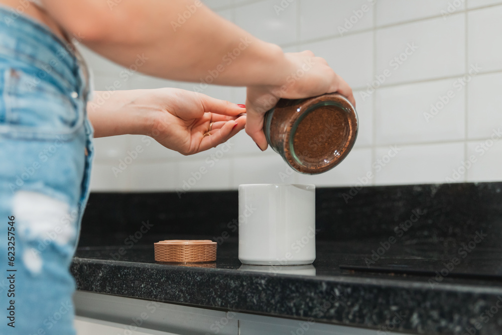 Detail shot of a woman's hands preparing coffee in the kitchen of her home.