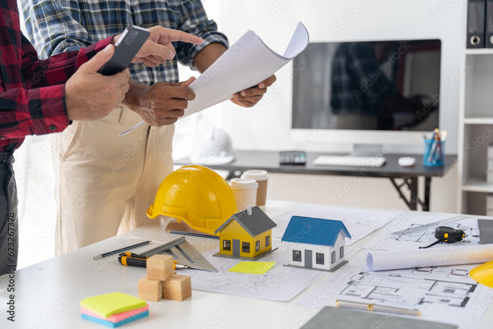 Engineer and contractor planning projects together at desk with blueprints. Engineer and contractor planning projects together at desk with blueprints.