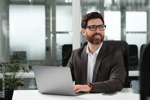 Man working on laptop at white desk in office. Space for text