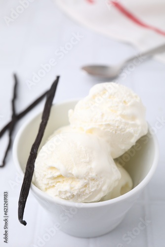 Delicious ice cream and vanilla pod on white table, closeup