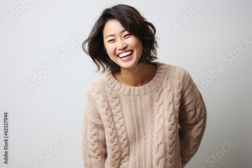 Young beautiful asian woman laughing and looking at the camera in studio