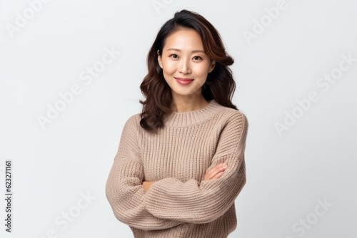 Portrait of a smiling young asian woman standing with arms crossed over white background