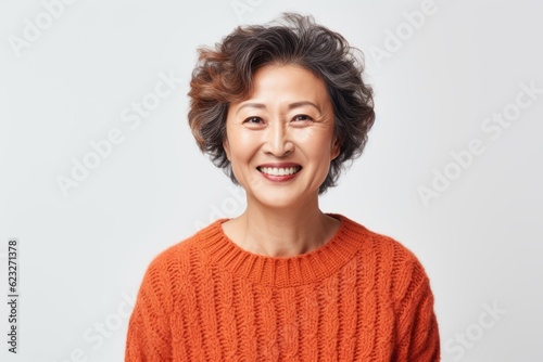 Portrait of a smiling mature asian woman in red sweater looking at camera over white background