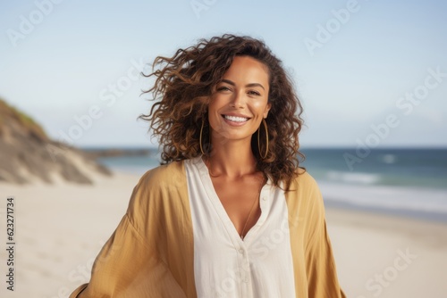 Portrait of a smiling young woman with curly hair on the beach