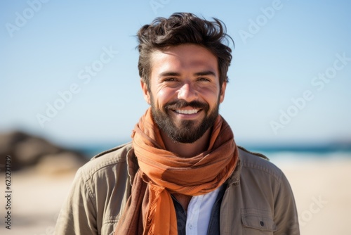 Portrait of a handsome young man smiling at the camera on the beach