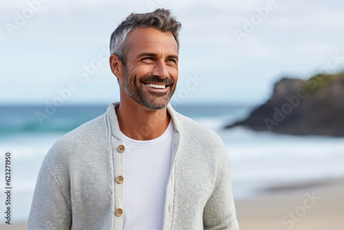 Portrait of smiling mature man standing on beach at the day time