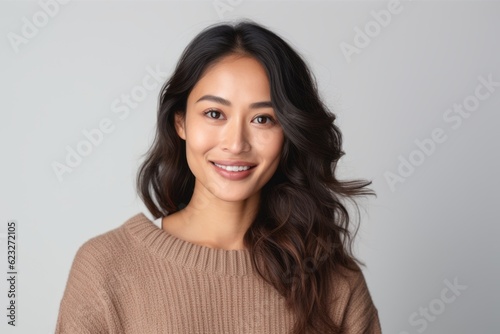 Portrait of a beautiful asian woman smiling and looking at camera over gray background
