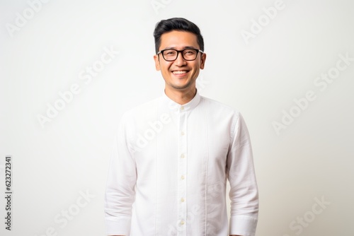 Young handsome Indian man wearing glasses and a white shirt standing and smiling