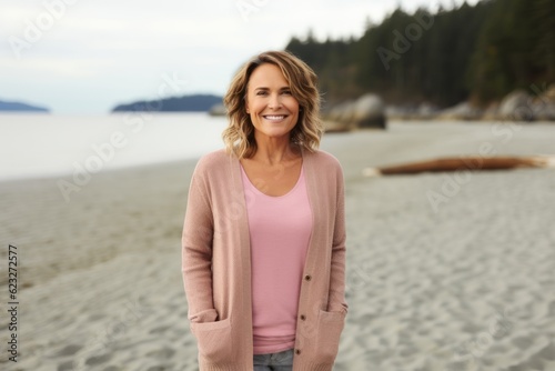 Portrait of smiling middle aged woman standing on beach looking at camera