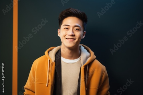 Portrait of a young asian man in yellow coat on dark background