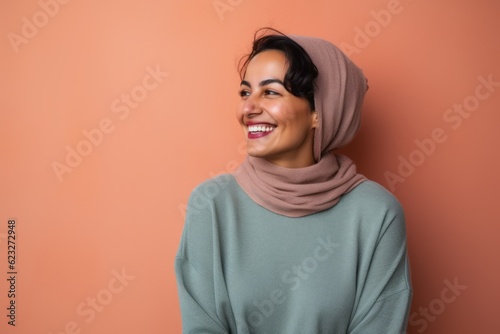 Portrait of a beautiful young woman wearing a headscarf against orange background © Leon Waltz