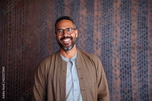 Portrait of a smiling man wearing eyeglasses standing against wall