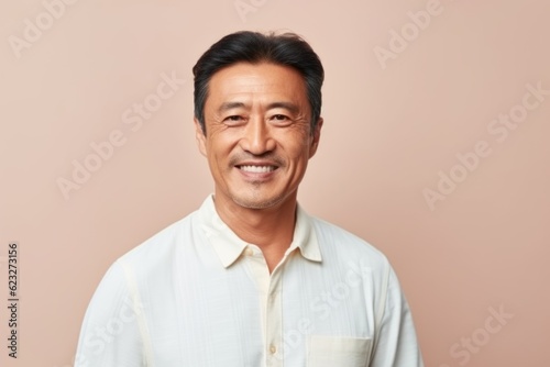 Portrait of a smiling asian man looking at camera isolated over beige background