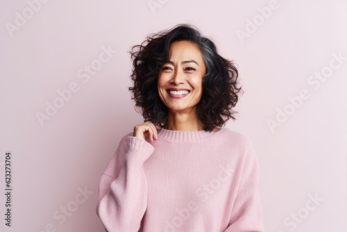 Portrait of a smiling young woman in a pink sweater on a pink background