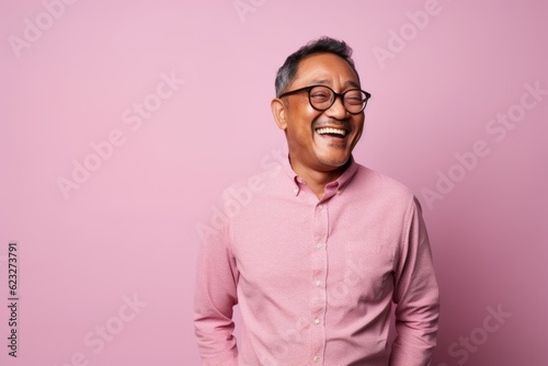 Portrait of a smiling asian man in glasses on a pink background © Leon Waltz