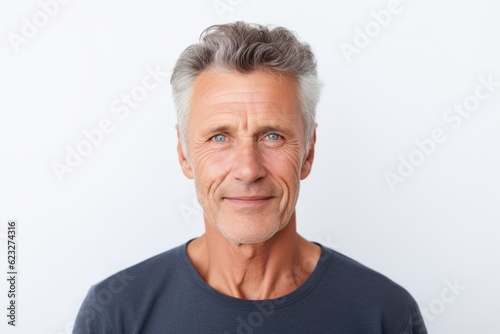 Thoughtful mature man looking at camera while standing against white background