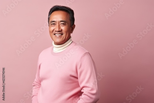Portrait of a smiling asian man in pink sweater against pink background