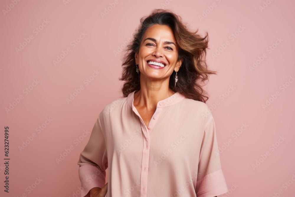 Portrait of a beautiful young woman laughing and looking at camera isolated over pink background
