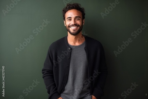 Portrait of a handsome young man standing against a green chalkboard