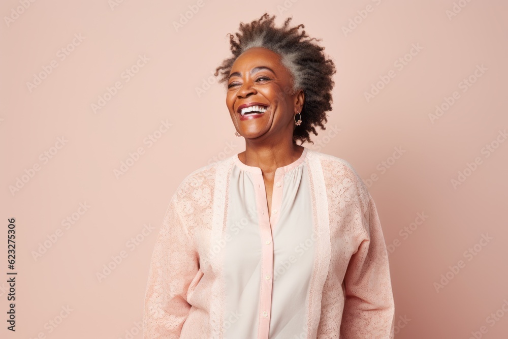 Fototapeta premium Portrait of a beautiful african american woman laughing against pink background