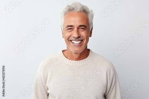 Medium shot portrait photography of a satisfied Brazilian man in his 60s wearing a cozy sweater against a white background 