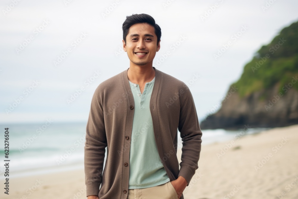 Portrait of smiling young man standing with hands in pockets at beach Portrait of smiling young man standing with hands in pockets at beach