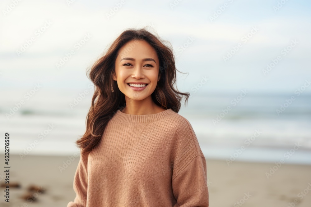 happy asian woman in beige sweater looking at camera on beach happy asian woman in beige sweater looking at camera on beach
