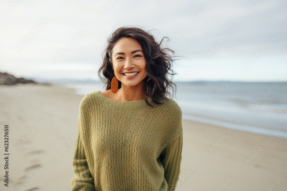 Portrait of a smiling young woman in sweater standing on the beach Portrait of a smiling young woman in sweater standing on the beach