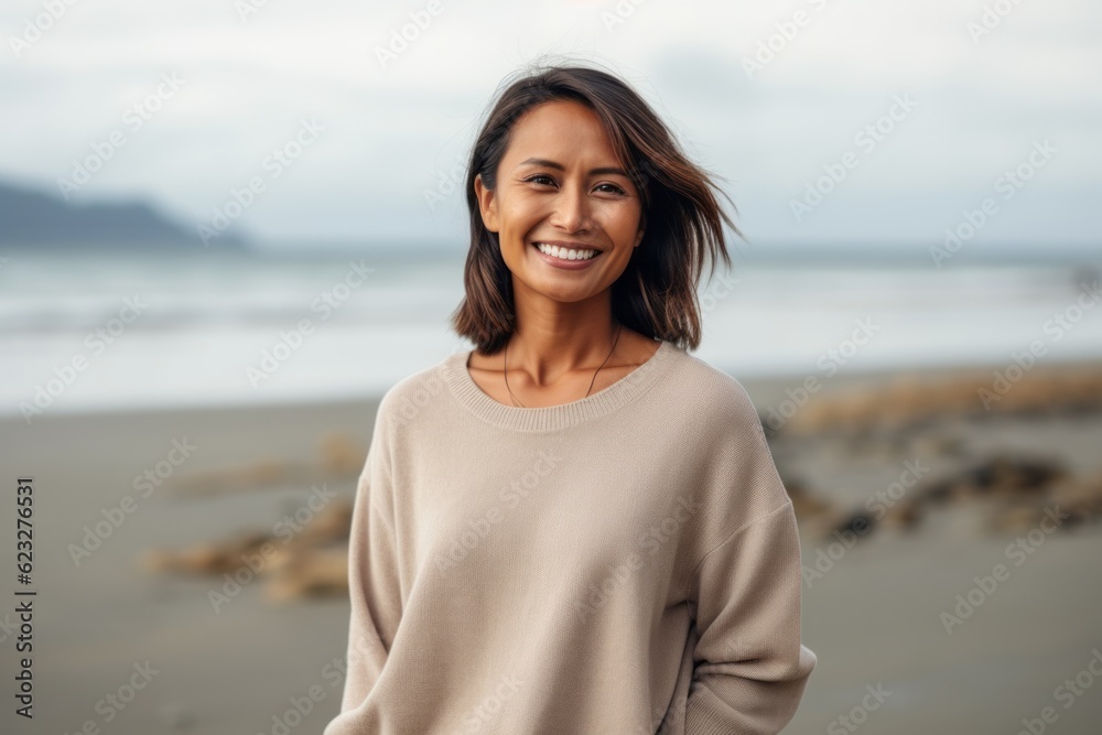 Portrait of a smiling young woman standing on the beach and looking at camera Portrait of a smiling young woman standing on the beach and looking at camera