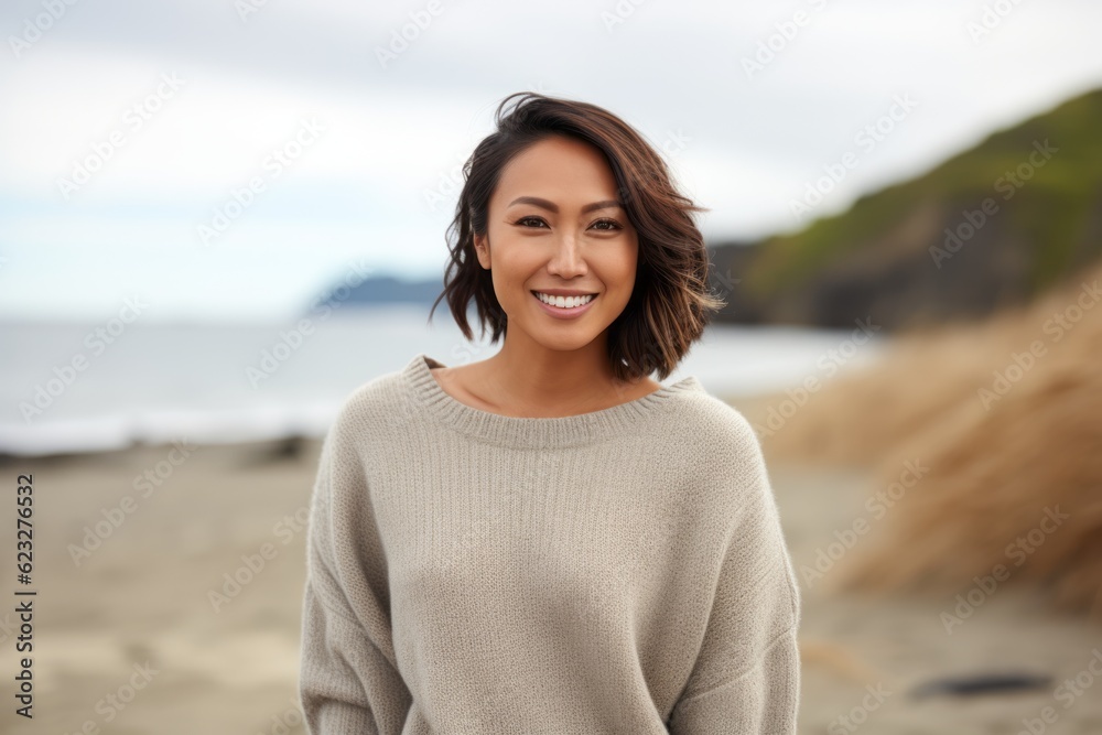 Portrait of a smiling young woman standing on the beach, looking at camera Portrait of a smiling young woman standing on the beach, looking at camera