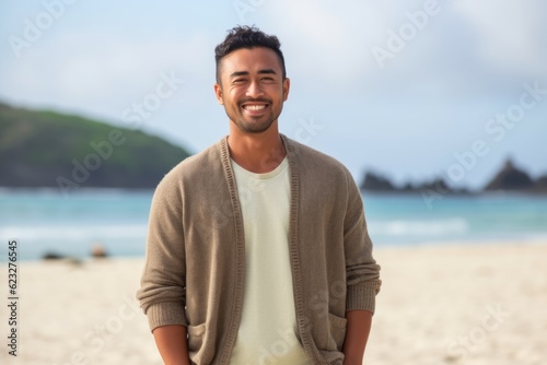 Portrait of a handsome young man standing on the beach and smiling
