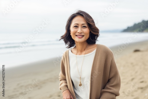 Portrait of a happy mature woman standing on the beach and looking at camera