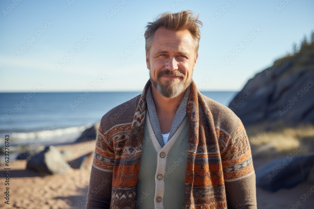 Portrait of handsome man wrapped in plaid on beach in autumn Portrait of handsome man wrapped in plaid on beach in autumn