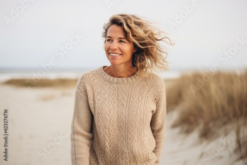 Lifestyle portrait photography of a tender Russian woman in her 40s wearing a cozy sweater against a beach background 