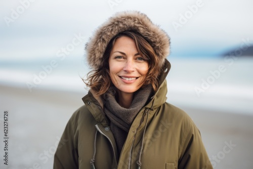 Portrait of smiling woman in winter jacket on beach at cold day © Anne Schaum