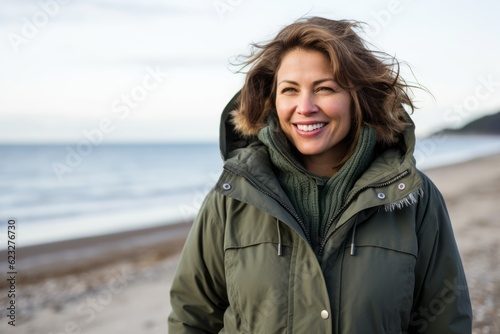 Portrait of smiling woman standing on beach in winter clothes looking at camera © Anne Schaum