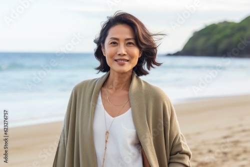 Portrait of smiling asian woman standing on beach at seaside