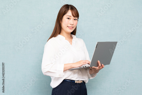 立ってパソコン操作をする女性右向き