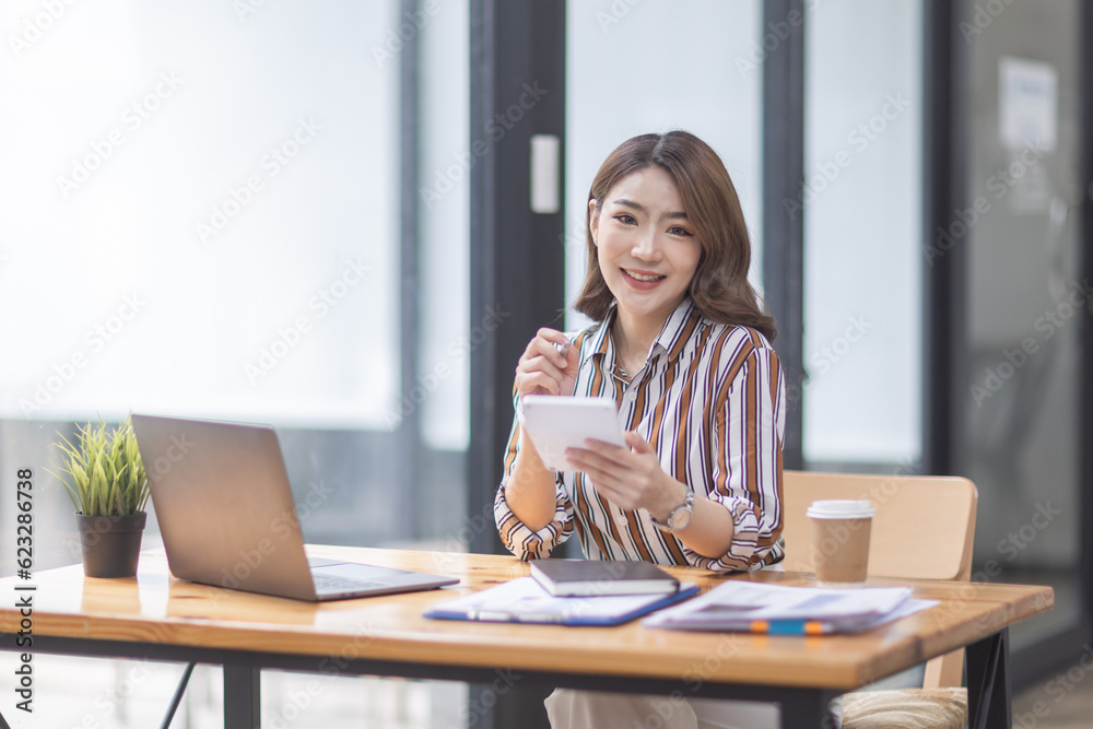 Asian Businesswoman Using laptop computer and working at office with calculator document on desk, doing planning analyzing the financial report, business plan investment, finance analysis concept.
Asian Businesswoman Using laptop computer and working at office with calculator document on desk, doing planning analyzing the financial report, business plan investment, finance analysis concept.