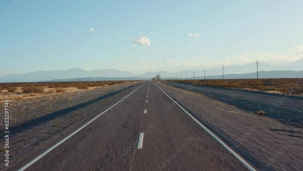 Aerial view of highway through desert-like valley during the daytime, drone flying up above the asphalt road with dry trees and grass on side Aerial view of highway through desert-like valley during the daytime, drone flying up above the asphalt road with dry trees and grass on side
