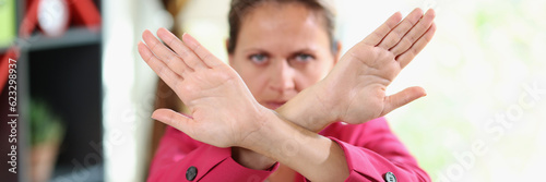 Woman with serious face shows crossed arms as symbol of no, stop, denied and refuse.