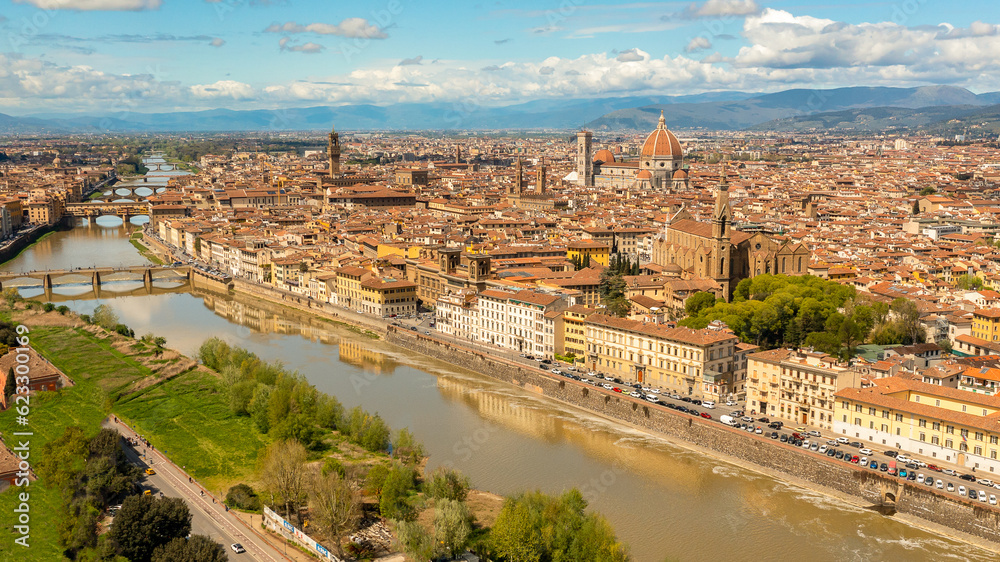 Aerial daytime landscape photo of Florence, Italy, as seen from the Piazzale Michelangelo viewpoint. The Cathedral of Santa Maria del Fiore and the Ponte Vecchio bridge are visible.