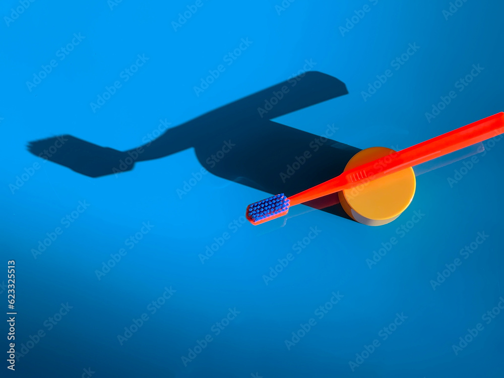 Fototapeta premium Bright orange toothbrush on a blue background. Dental care. Morning routine