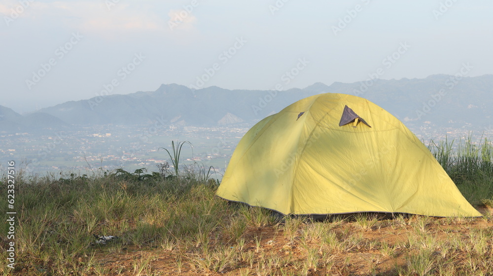 Camping tent on a hill with mountains in the background in the morning