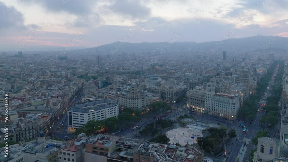 Aerial panoramic view of metropolis. Famous Placa de Catalunya surrounded by historic palaces. Hazy view of cityscape at dusk. Barcelona, Spain Aerial panoramic view of metropolis. Famous Placa de Catalunya surrounded by historic palaces. Hazy view of cityscape at dusk. Barcelona, Spain
